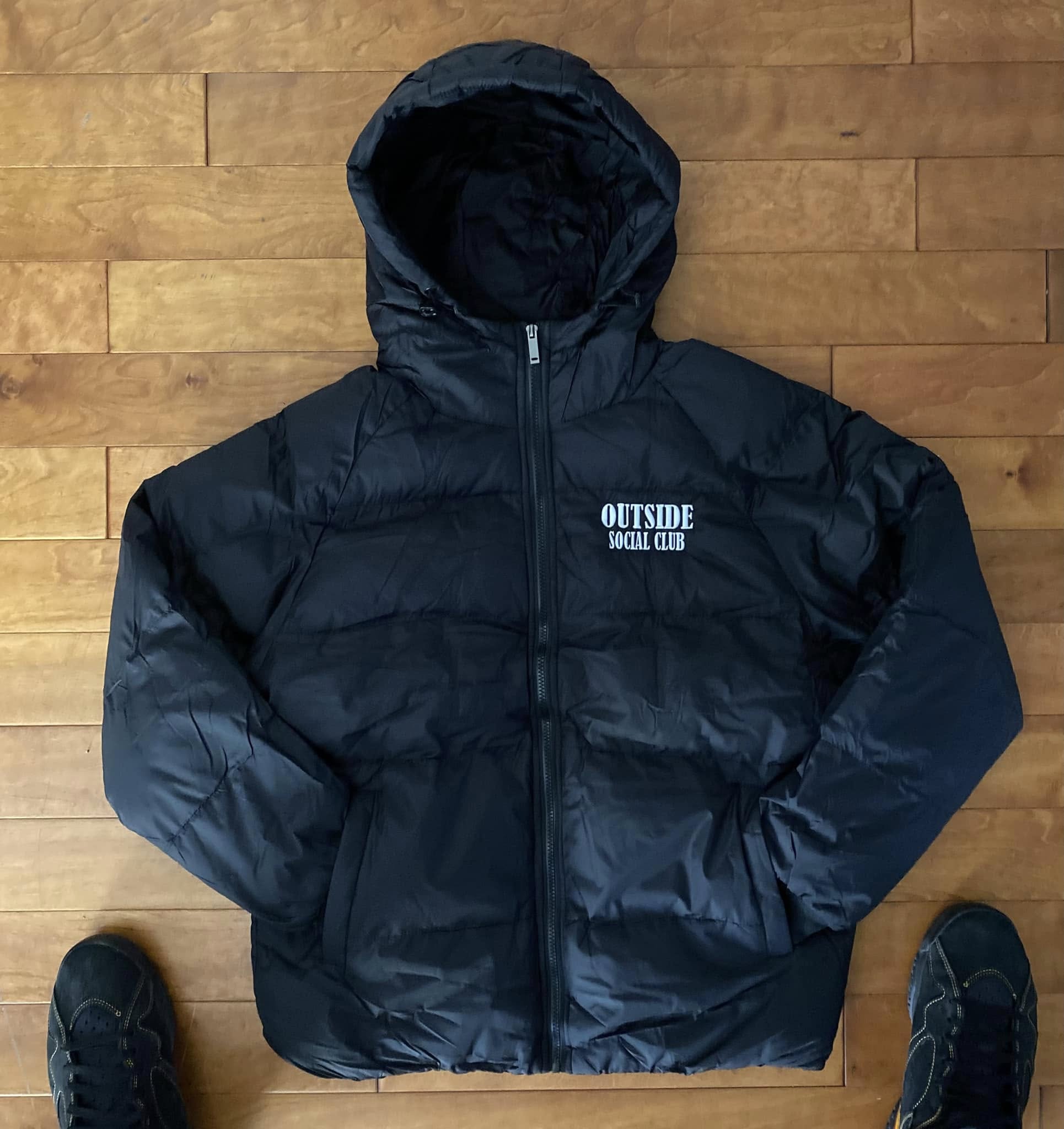 Black puffer jacket with 'Outside Social Club' logo on a wooden floor